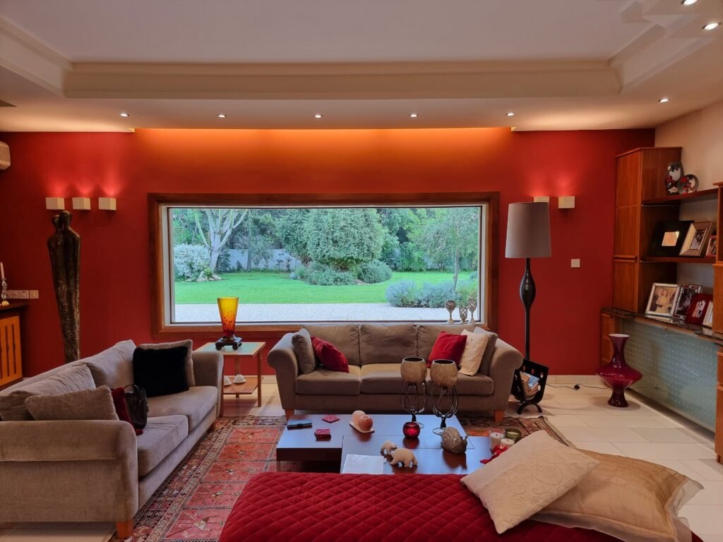 أفضل شركة أصباغ وديكور في أبوظبي 0556485364 A warm and inviting living room with a large window overlooking a lush garden.