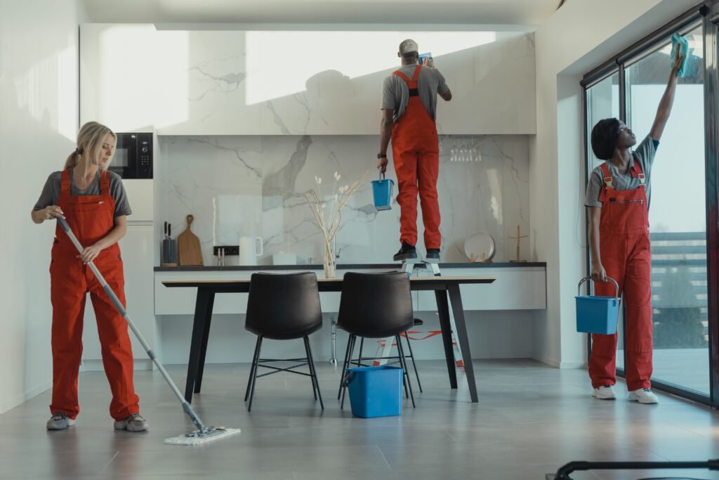أفضل شركة تنظيف قصور في العين0556485364 Group of cleaners in red uniforms mopping and wiping glass in a modern dining room.